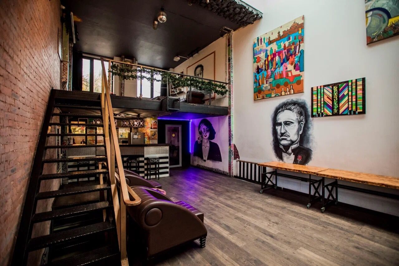 Арендовать Street Art Loft (Стрит Арт Лофт). Лофт-пространство с деревянным полом, черным потолком, металлической лестницей на второй этаж. Кожаные диваны, деревянные столы. Стены украшены крупными граффити и картинами. Яркое освещение и неоновая подсветка.