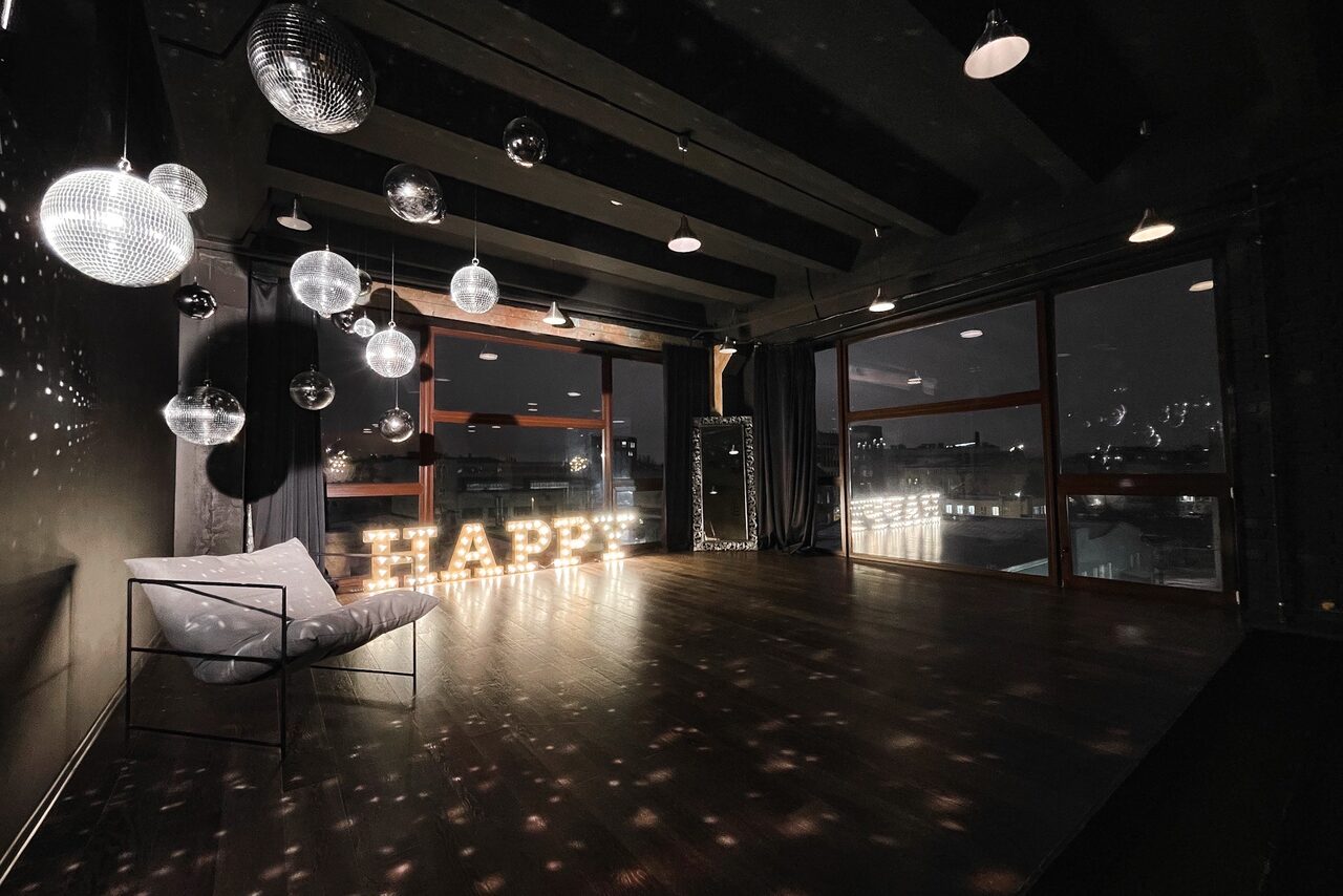Арендовать Стильный панорамный лофт на Петроградке. Диско-шар. Играющий свет. Подсвеченные буквы HAPPY. Профессиональная лампа. Диван, книжная полка