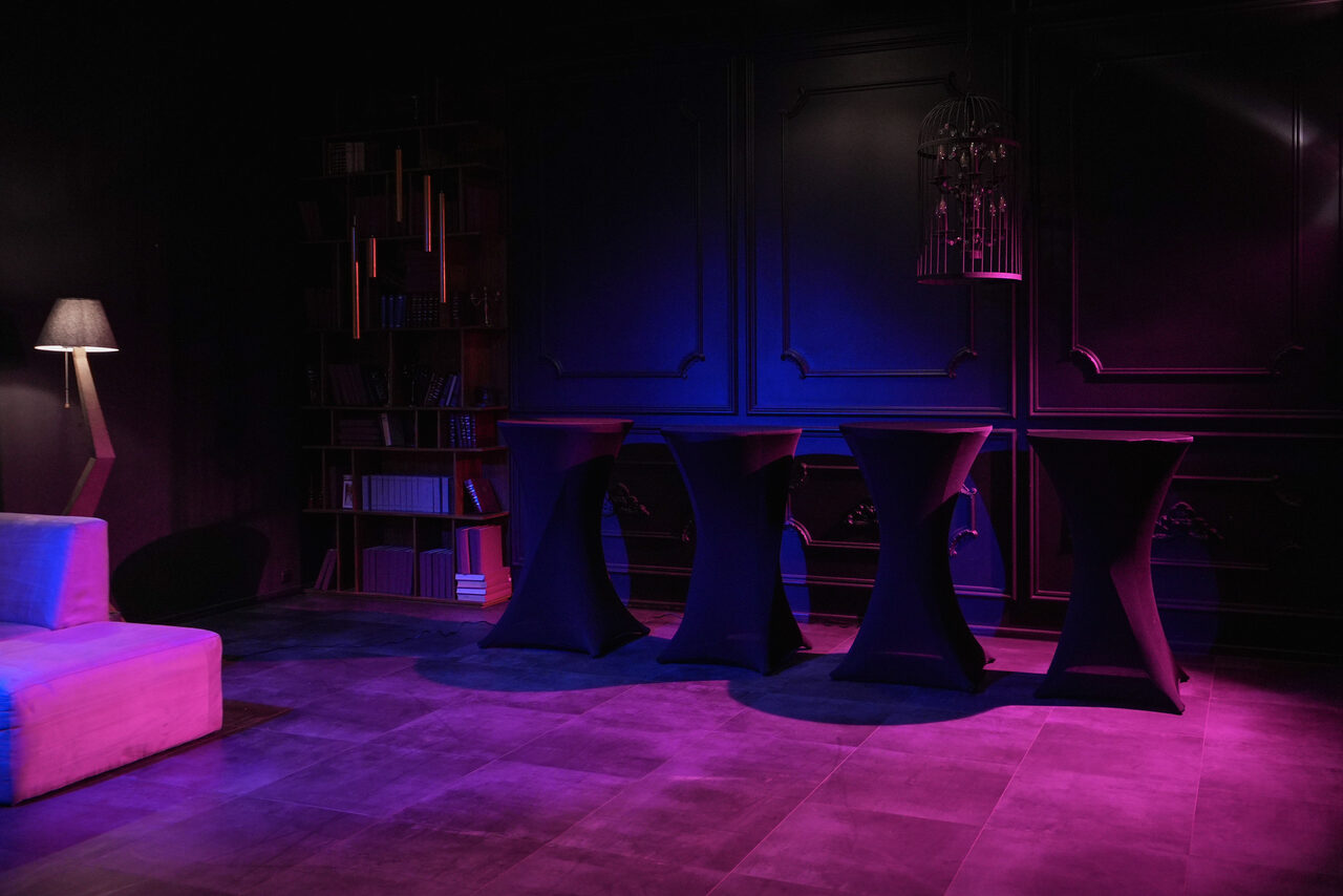 Арендовать Стильный панорамный лофт на Петроградке. Большой круглый стол с чёрной скатертью и посудой. Декоративные цветы. 