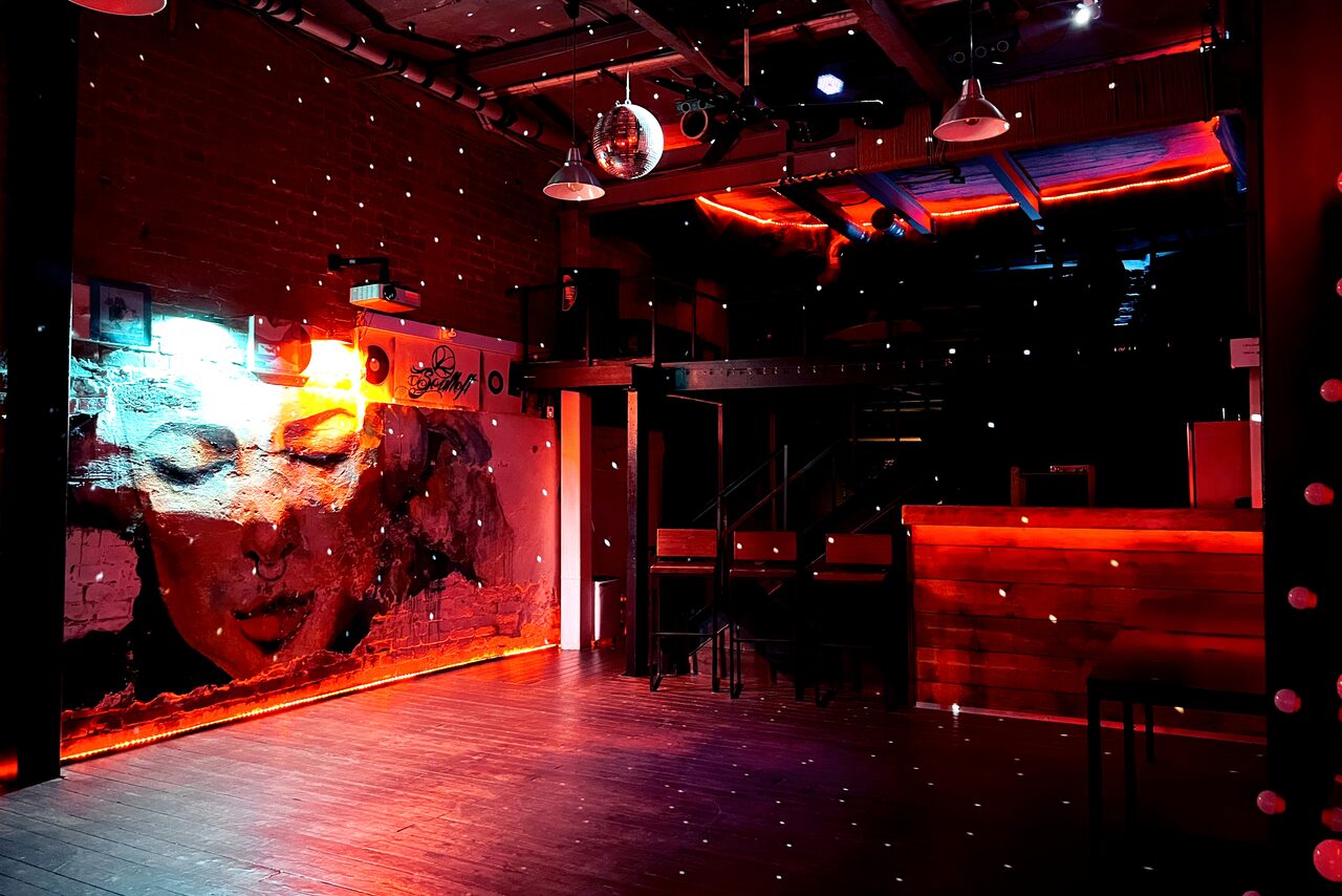 Арендовать Soul Loft . Девушки сидят полке в яркой комнате лофта, позируют на камеру, все улыбаются 