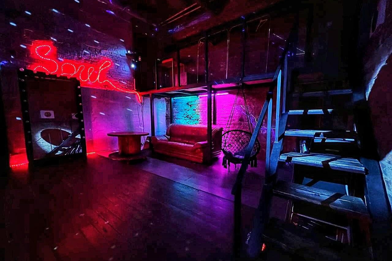 Арендовать Soul Loft . Светлая комната лофта, девушки проводят творческое мероприятие, суша фенами свои рисунки. Стоит большой стол. на них лежат разноцветные краски. На заднем плане шарики и большое зеркало