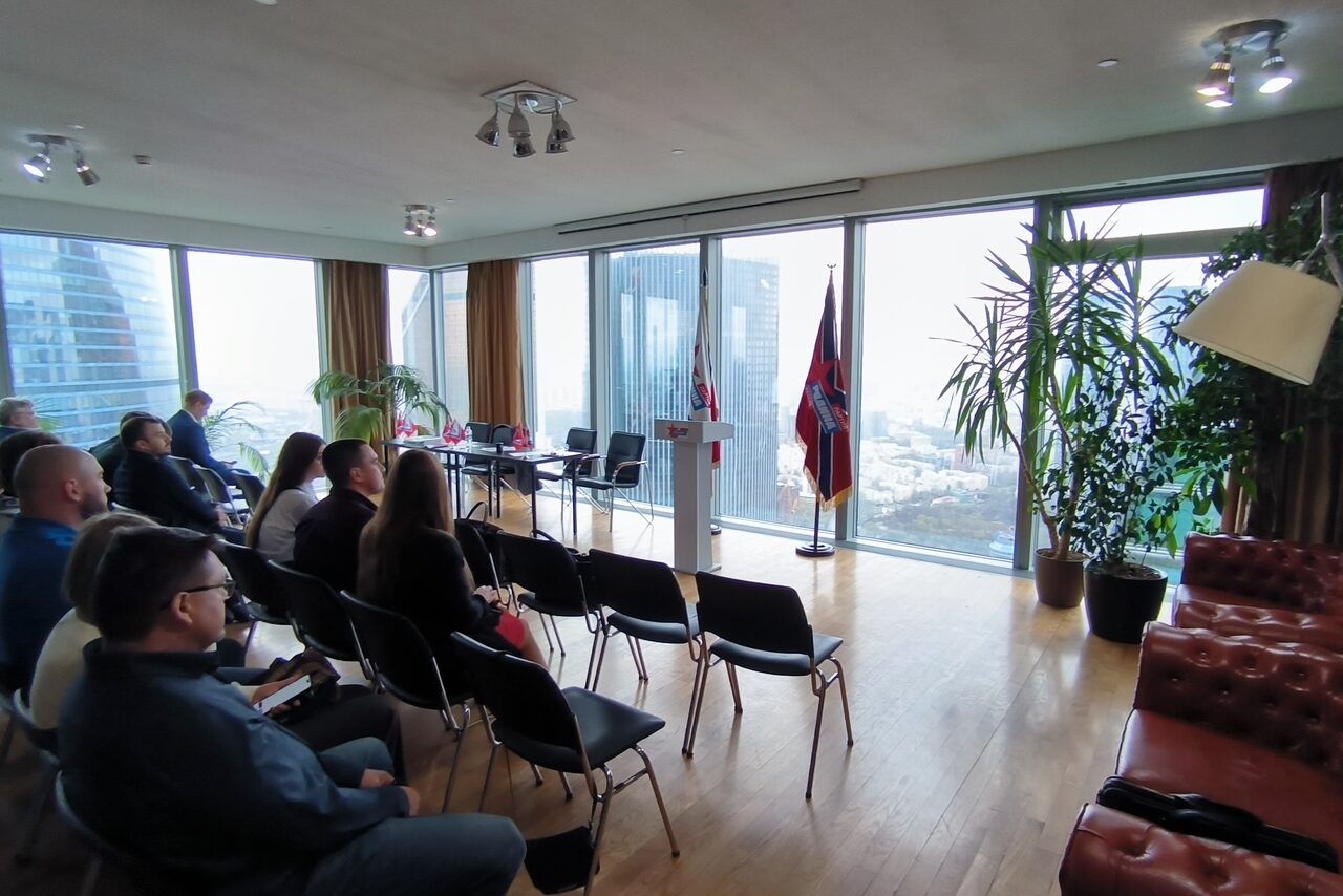 Арендовать Space on the 60th floor with panoramic views. Просторная комната с панорамными окнами, деревянный пол, стулья для зрителей и красный кожаный диван. Имеется трибуна, комнатные растения, флаги. Освещение естественное плюс точечные светильники на потолке.
